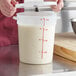 A hand holding a white Choice food storage container lid.