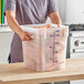 A woman holding a Choice translucent plastic container full of carrots.