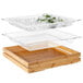 A Rosseto clear acrylic tray with glass containers on a bamboo shelf over ice.