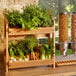 A Rosseto natural bamboo display stand with vegetables on the shelves.