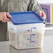 A person holding a Choice translucent square plastic container with spiral pasta and a blue lid.