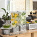A table with a Rosseto clear acrylic beverage dispenser with fruit inside.