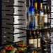 A Rosseto stainless steel display riser on a table with wine bottles and appetizers.