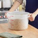 A person holding a Choice translucent plastic container filled with pasta.