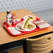 A red Choice fast food tray with a sandwich and other food on it.