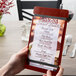 A person holding a mahogany wood menu board with rubber band straps.