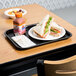 A Choice black plastic fast food tray with a sandwich and a bottle of juice on it.