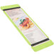 A lime green wood menu board with rubber band straps holding a menu with a picture of spaghetti.