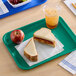 A teal plastic fast food tray holding a sandwich, an apple, and a cup of iced beverage.