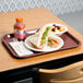 A Choice burgundy plastic fast food tray with a sandwich and fruit.