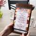 A hand customizing a walnut wood menu board on a table.