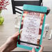 A person holding a Menu Solutions sky blue wood menu board with rubber band straps.