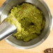 A Fox Run stainless steel mortar and pestle with green sauce in it.