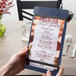 A person holding a Menu Solutions wood menu board with rubber band straps.