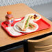 A red plastic Choice fast food tray with a sandwich and fruit on it.