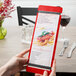 A person holding a Menu Solutions wood menu board in front of a wine glass.