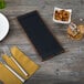 A walnut wood menu board with top and bottom strips on a wood table with a bowl of nuts.