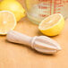 A wooden table with lemons and a Franmara beechwood squeezer.