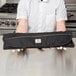 A man holding a Mercer Culinary white handled knife roll set on a counter.