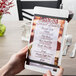 A hand holding a Menu Solutions white wood menu board with rubber band straps.