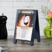 A Menu Solutions denim wood sandwich menu board tent with a clip holding a menu.