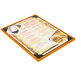 A Menu Solutions Country Oak wood menu board with picture corners holding a menu on a table.