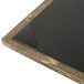 A weathered walnut wood menu board with picture corners on a table.