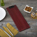 A mahogany wood clipboard with a fork and knife on it next to a plate and bowl of nuts.