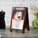 A walnut wood Menu Solutions sandwich board tent with a menu on it.
