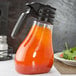 A Tablecraft Tritan dispenser bottle on a table with a salad.