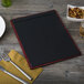 A mahogany wood Menu Solutions board with top and bottom strips on a wood table with a plate and fork.