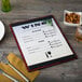 A customizable mahogany wood menu board on a table with a menu, fork, and knife.