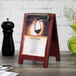 A Mahogany wood menu board tent with a menu on a table.