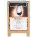 A Menu Solutions weathered walnut wood sandwich menu board tent with clip on a table holding a menu.
