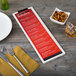 A customizable wood Menu Solutions clip board on a table with a menu, fork, and knife.