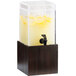 A Cal-Mil bamboo beverage dispenser with a black spigot filled with lemonade and lemon slices on a wooden base.