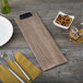 A weathered walnut wood clipboard holding a menu next to a plate and bowl of nuts.