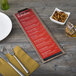 A customizable wood menu clip board on a table with a green glass and a bowl of nuts.