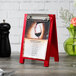 A Menu Solutions berry wood menu tent with a clip on a table with a menu on it.