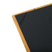 A customizable wood menu board with picture corners on a table.