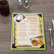 A Menu Solutions wood menu board with picture corners on a table with a menu featuring a picture of a meal.