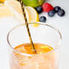 A gold Barfly classic bar spoon in a glass of lemonade with a metal straw and a lemon slice.