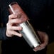 A person holding a Barfly stainless steel cocktail shaker.