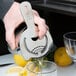 A hand using a Barfly stainless steel Hawthorne strainer to pour a cocktail into a glass.