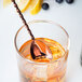 A Barfly copper plated Japanese style bar spoon in a glass of liquid.