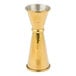 A gold colored metal Barfly Japanese style jigger on a table.