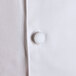 A close up of a Chef Revival white long sleeve chef coat with a button.