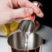 A person using a Barfly copper Japanese style jigger to pour liquid into a cup.