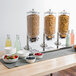 A table with a Choice cereal dispenser and bowls of cereal and berries.