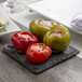 An Acopa black slate plate with food on it on a table.